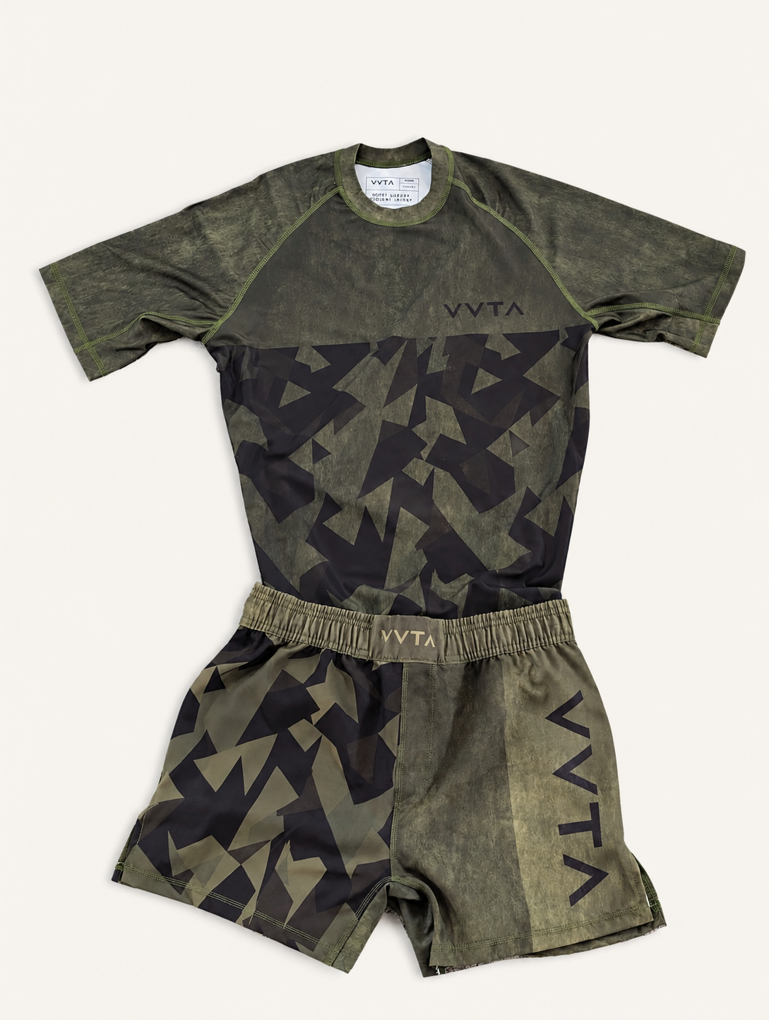 A matching athletic set consisting of a long-sleeve jersey and shorts in olive green and black camouflage, laid flat on a light beige background. The jersey features 'VYTA' printed on the sleeve and chest, and the shorts feature 'VYTA' printed on the waistband.